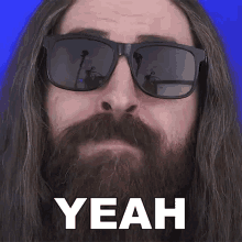 a man with long hair and a beard is wearing sunglasses and says " yeah "