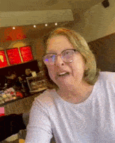 a woman wearing glasses is sitting at a table in a cafe