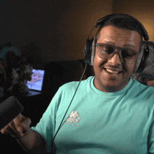 a man wearing headphones and a kappa shirt smiles while holding a microphone