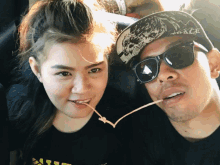 a man and a woman are posing for a picture and the man is wearing a hat that says peace