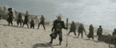 a group of people standing on a sandy beach including a man in a samurai costume