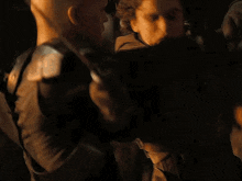 a bald man is standing in a dark room holding a person 's arm .