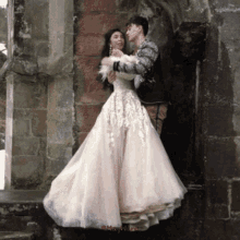 a man kisses a woman on the cheek in front of a brick building