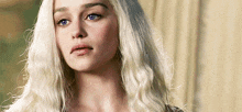 a woman with blonde hair and blue eyes looks at the camera .