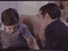 a man and a boy are playing with each other and the boy is holding the man 's hand .