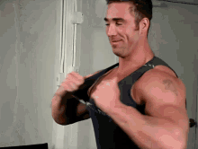 a man with a tattoo on his arm is wearing a black tank top
