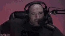 a man wearing headphones and a microphone is sitting in front of a microphone .
