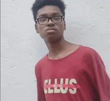 a young man wearing glasses and a red shirt that says " plus " on it