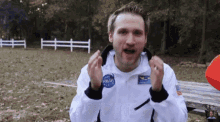 a man is wearing a nasa jacket and making a funny face .
