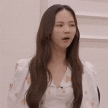 a woman with long hair is making a funny face while wearing a white shirt .