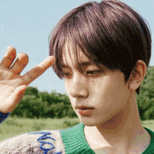 a young man with purple hair is wearing a green sweater with the word moon on the sleeve
