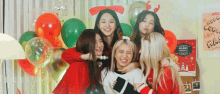 a group of young women are posing for a picture in front of balloons and a sign that says merry christmas