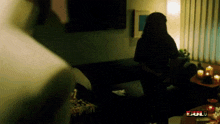 a woman is standing in a living room with candles on a table and the word full on the bottom