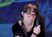 a woman wearing glasses and headphones is holding a microphone in her hand