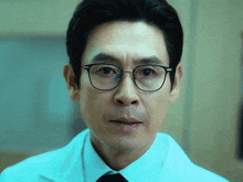 a man with glasses and a white coat looks at the camera