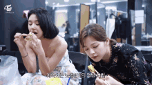 two women are eating food with twice tv written on the bottom right