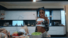 a woman in a crop top that says hot is standing in a kitchen