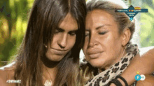 a woman with long hair is hugging another woman who is crying