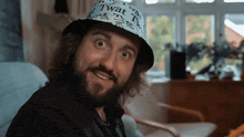 a man with a beard wears a hat that says twat on it