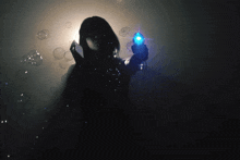 a woman in a dark room is holding a blue object