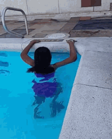 a woman in a purple bikini is swimming in a swimming pool .