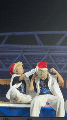 a man wearing a santa hat holds another man 's head