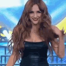 a woman in a black dress is dancing on a stage and smiling .