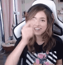 a woman wearing headphones and a black and white shirt is sitting in a gaming chair .