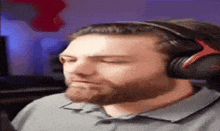 a man with a beard is wearing headphones and making a funny face .