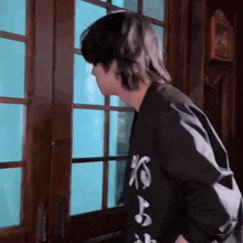 a man in a black shirt is standing in front of a door looking out .