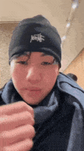 a young man wearing a black hat and scarf is holding a cell phone .