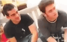 two young men are sitting next to each other on a couch and smiling .