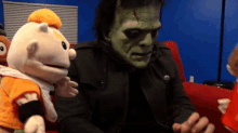 a man in a frankenstein costume is sitting on a red couch