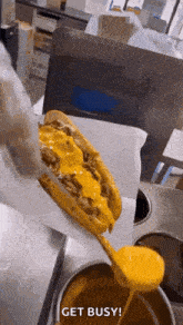 a person is pouring cheese sauce on a hot dog .
