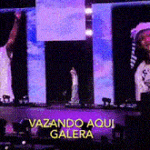 a man is standing on a stage with a sign that says vazando aqui galera on it
