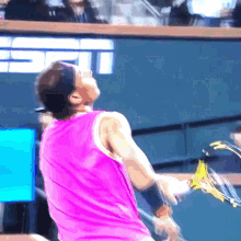 a man in a pink tank top is holding a tennis racquet in front of a wall that says espn