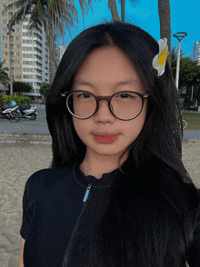 a girl with glasses and a flower in her hair looks at the camera