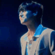 a man in a suit is smiling in front of a blue background .