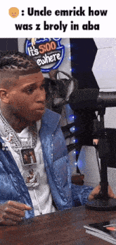 a man in a blue jacket sitting in front of a microphone with a sign that says it 's 5:00 everywhere