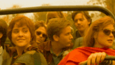 a group of people are sitting in a car with a woman wearing sunglasses