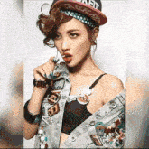 a woman wearing a denim jacket and a hat has a patch on her chest that says " watch "