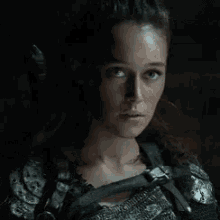 a close up of a woman wearing armor and a sword .
