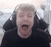 a man is wearing headphones and laughing with his mouth open .