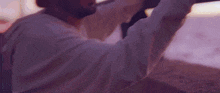 a man in a white shirt is holding a surfboard on a beach