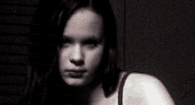a woman in a black bra looks at the camera in a dark room