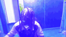 a person with dreadlocks and a mask with a cross on it