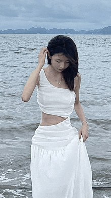 a woman in a white dress is standing in the ocean