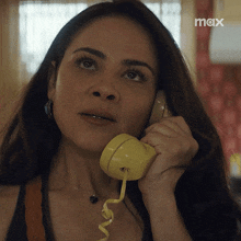 a woman talking on a yellow telephone with a max logo in the corner