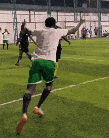 a man in a white shirt and green shorts is jumping in the air while playing soccer