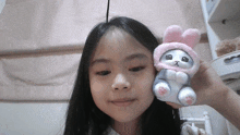 a little girl is holding a stuffed animal in a bunny hat